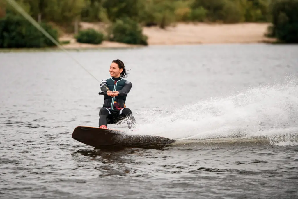 Person wakeboarding on a lake, smiling.